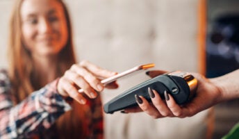 Young woman reaches out to pay with her smartphone in a shop or cafe