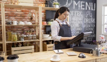 A woman using a POS machine in a coffee shop.