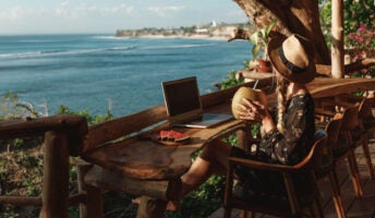 Woman in hat works from anywhere while drinking from coconut