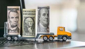 US Dollar bills, a trailer truck on a laptop computer