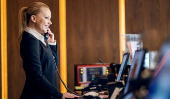 Hotel receptionist answers phone system at front desk