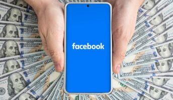 Facebook logo on blue screen in front of dollars