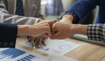 Businesspeople bump fists to celebrate successful project coordination and management