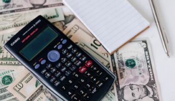Dollar bills and calculator on a table.