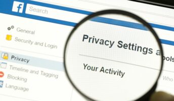 Hand holding a magnifying glass and magnifying the word "Privacy settings"