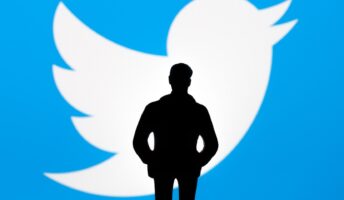 Elon Musk stood in front of Twitter logo